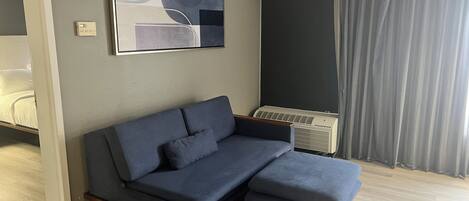 Un soggiorno moderno con un divano componibile, un condizionatore d'aria a muro e un grande quadro astratto.