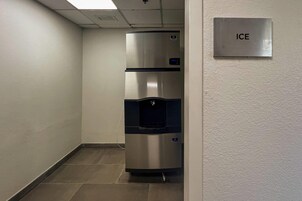 Un pasillo con un refrigerador de acero inoxidable y un dispensador de agua, y un cartel que dice 'ICE'.