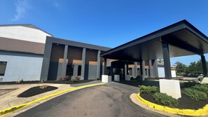 Un bâtiment moderne doté d’une entrée abritée, d’un parking avec des bordures jaunes et d’aménagements paysagers.