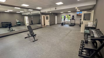 A gym with exercise equipment, a mirror, and a treadmill.