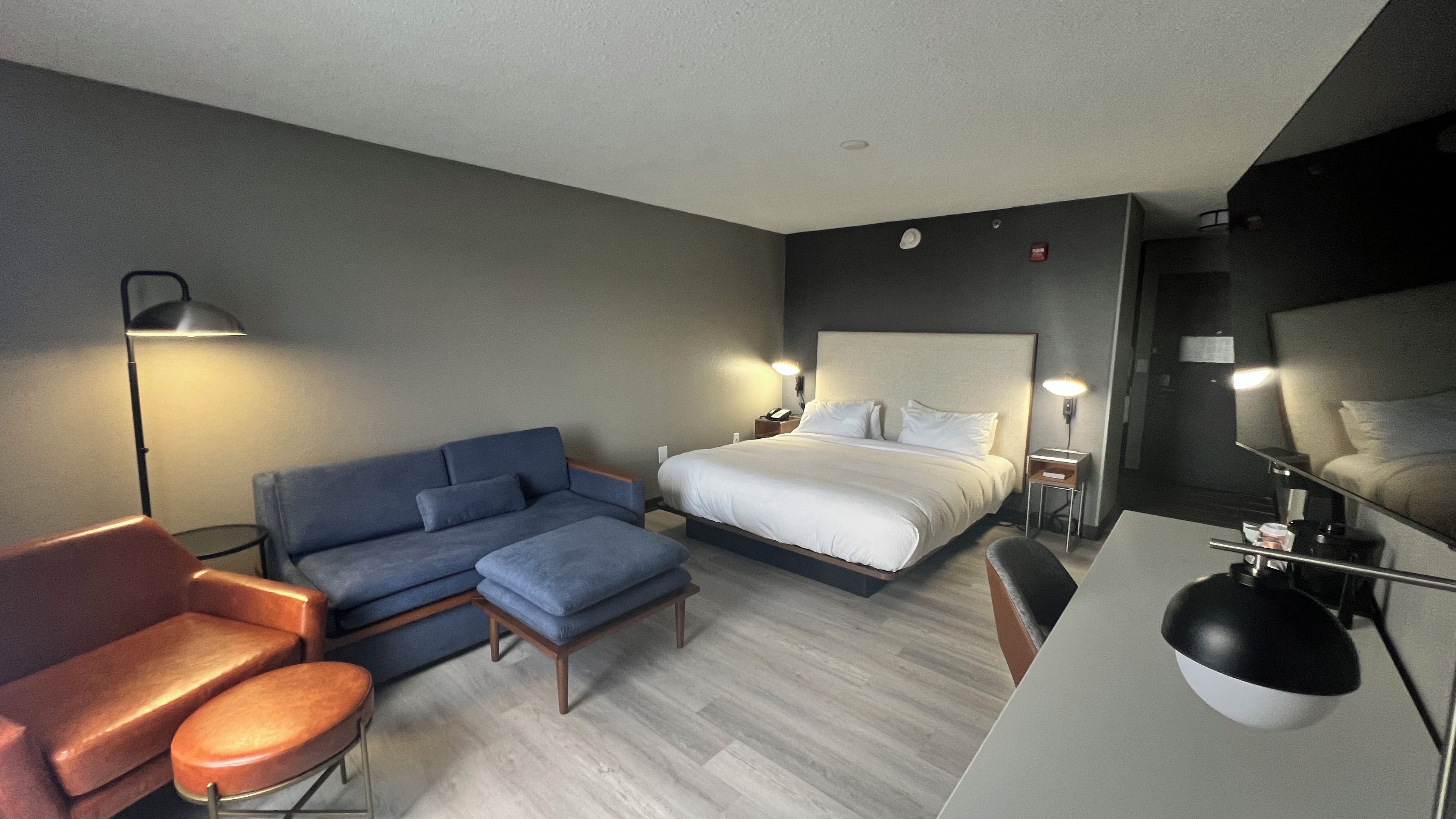 Ett hotellrum med en säng, en soffa, ett skrivbord och en stol.
