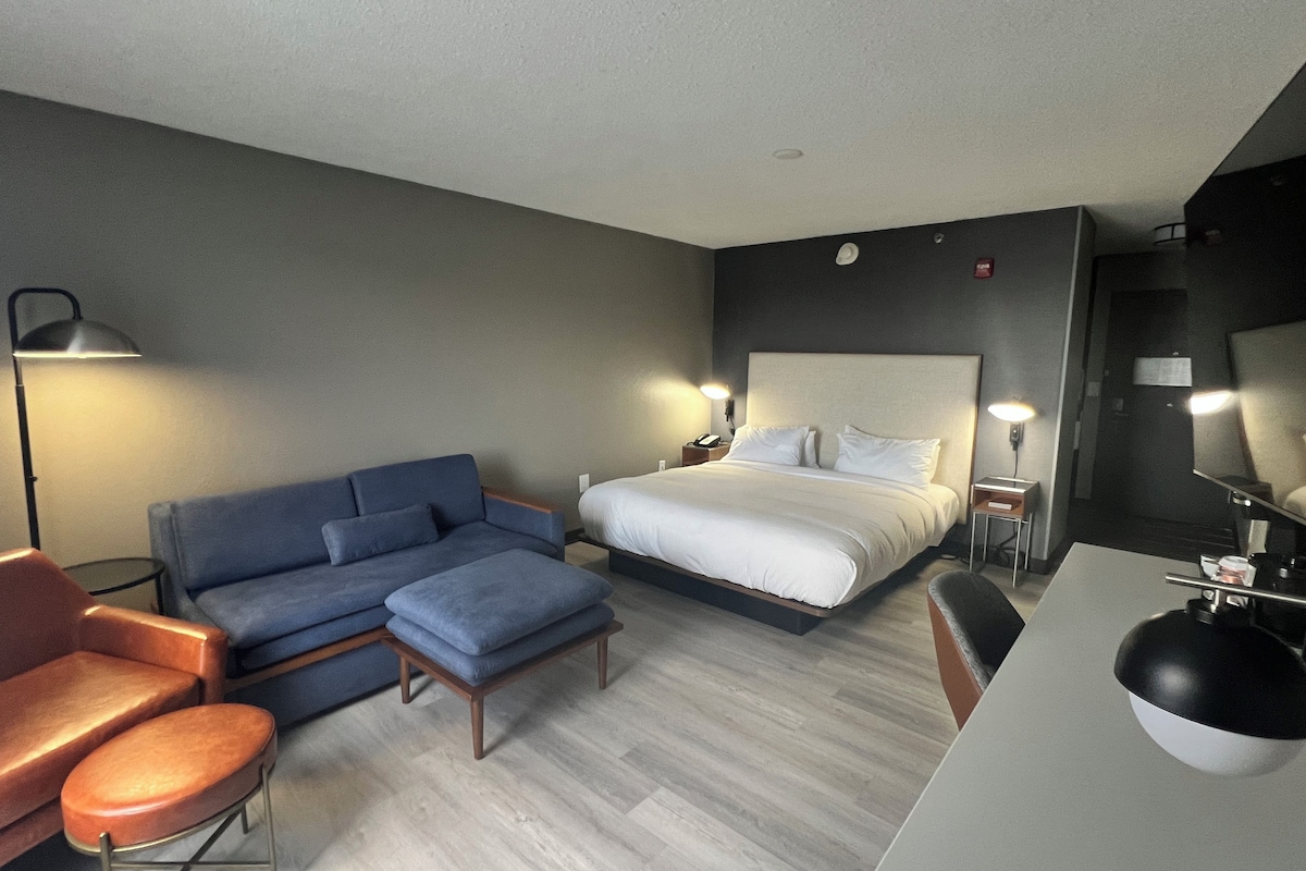 Een hotelkamer met een bed, een slaapbank, een bureau en een stoel.