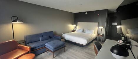 Ett hotellrum med en säng, en soffa, ett skrivbord och en stol.