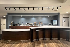 Zona de bar moderna con mostrador curvo, diversas opciones de asientos y una variedad de equipos.