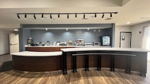 Een moderne keuken met een gebogen aanrecht, ingebouwde apparatuur en een plafond met inbouwspots.