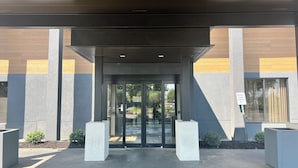 Entrada de un edificio con puerta de vidrio y un letrero de estacionamiento para personal de seguridad.