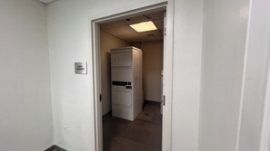 A narrow hallway with a door labeled 'GUEST LAUNDRY' leading to a laundry room with stacked appliances. - Comfort Inn Jackson North - Ridgeland (Jackson)