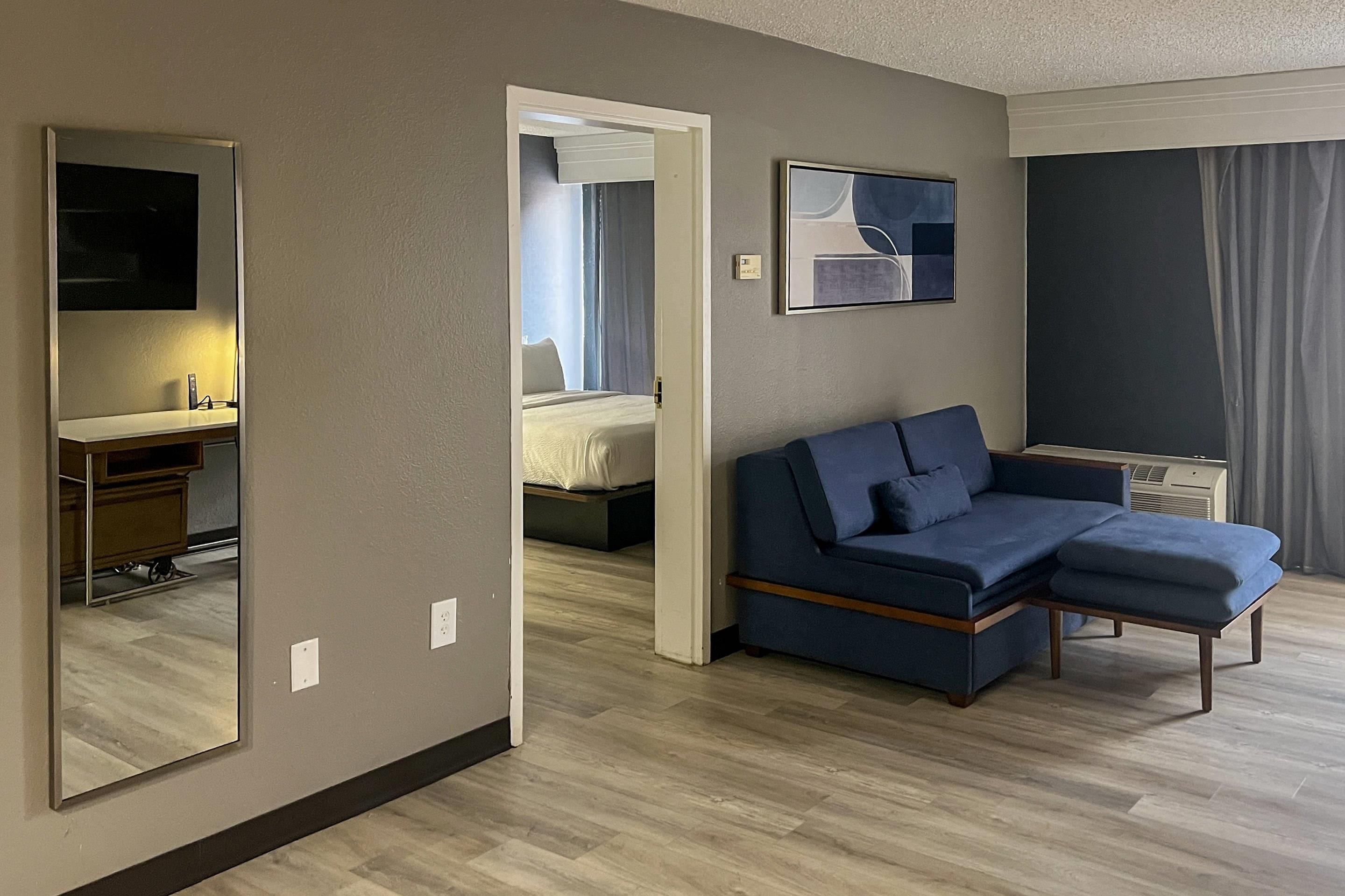 Een hotelkamer met een grote spiegel, een blauwe bank, een bed en een schilderij aan de muur.