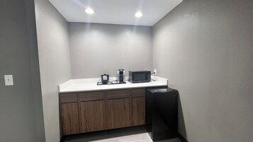 Una kitchenette pequeña equipada con microondas, cafetera y un basurero.