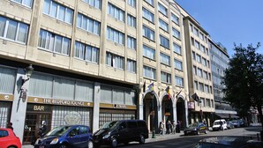 Un hotel de varios pisos con un bar en la planta baja, una agencia de viajes y un letrero de estacionamiento.