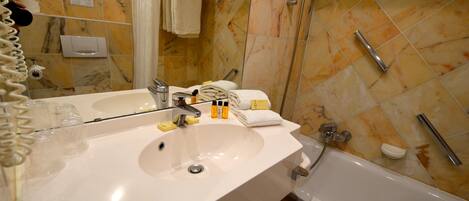 Un baño con lavamanos blanco, espejo y zona de ducha.