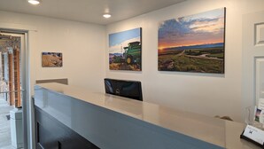 A reception desk with a computer, three landscape paintings, and a door to the left. - Henry's Fork Inn (St. Anthony)