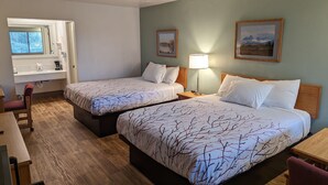 A hotel room with two beds, a desk, a chair, a window, and a bathroom. - Henry's Fork Inn (St. Anthony)
