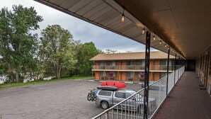 A motel with a covered parking area, a bicycle, and a red kayak. - Henry's Fork Inn (St. Anthony)