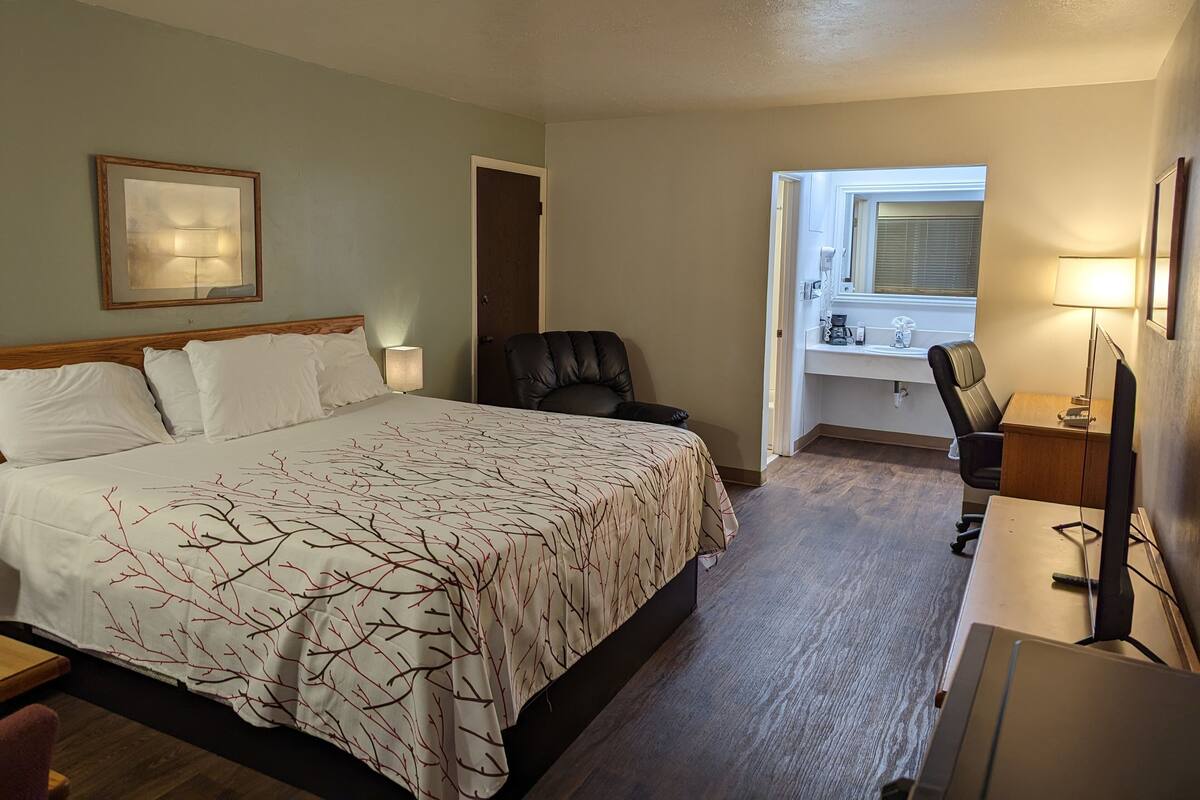 A hotel room with a bed, a desk, a chair, and a window.