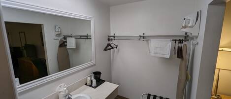 A bathroom with a white sink, mirror, towel rack, and a bench.