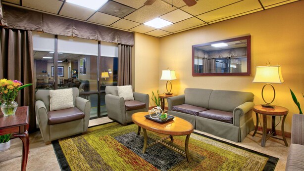 Ein Hotelzimmer mit einer Couch, zwei Sesseln, einem Couchtisch und einem kleinen Beistelltisch mit Lampen.