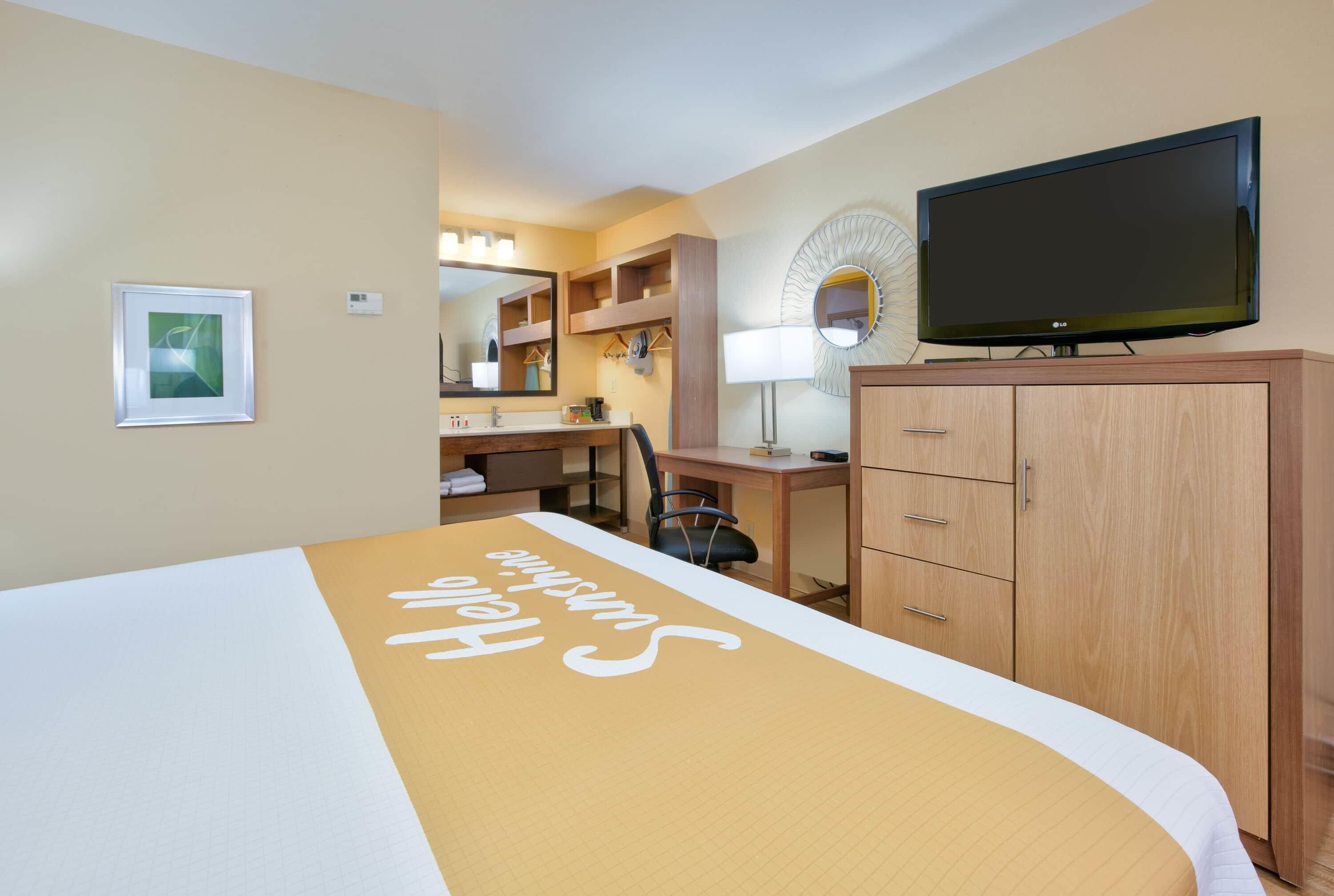 Une chambre d’hôtel équipée d’un lit, d’un bureau, d’une chaise, d’une télévision et d’une armoire.