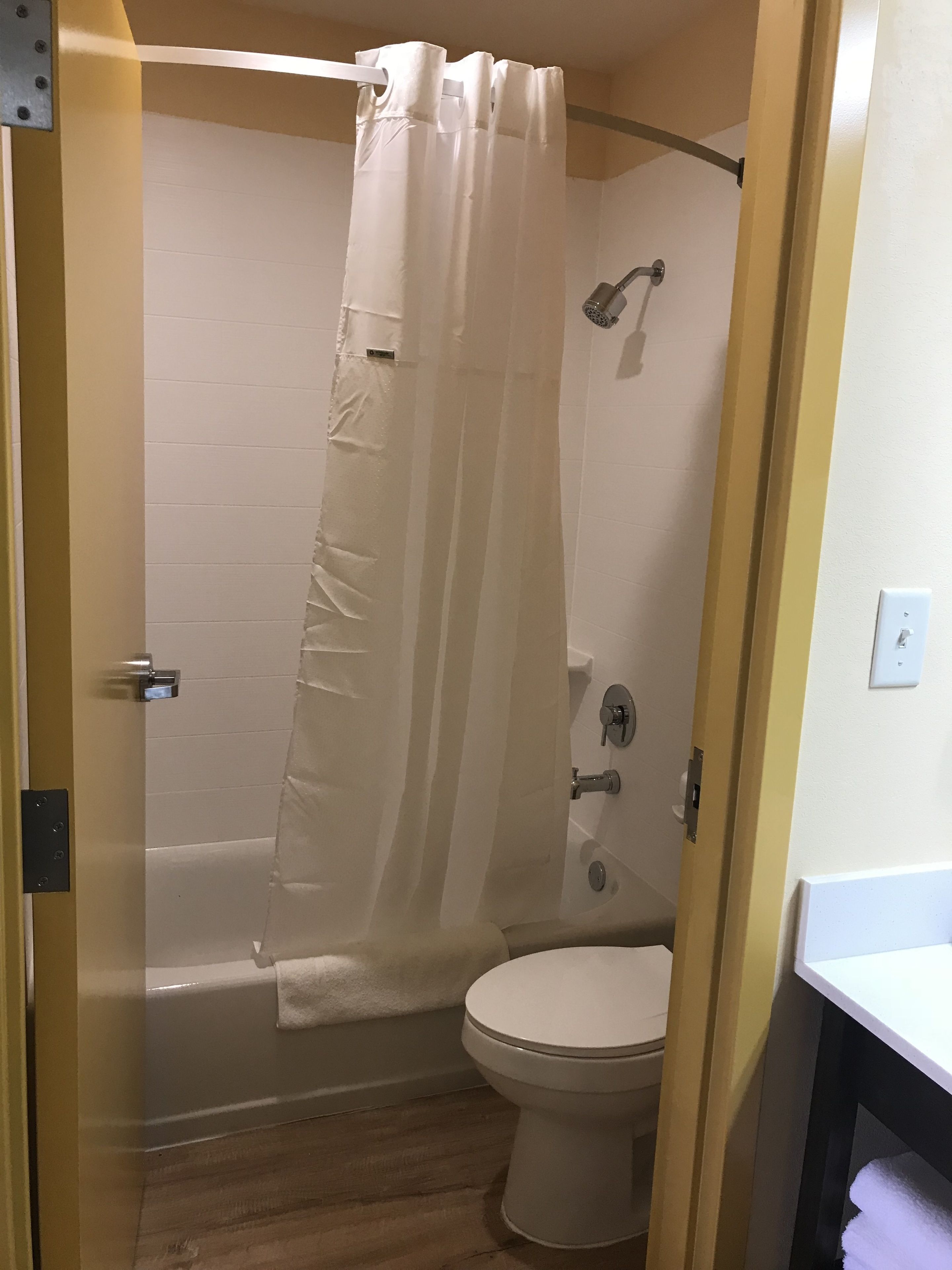 A bathroom with a shower, toilet, and a towel rack.