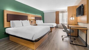 Habitación de hotel con dos camas, un escritorio, una silla, un televisor y una ventana con cortinas.