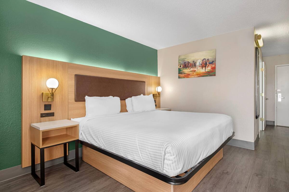Une chambre d’hôtel bien rangée, avec un lit, des tables de chevet et un tableau accroché au mur.