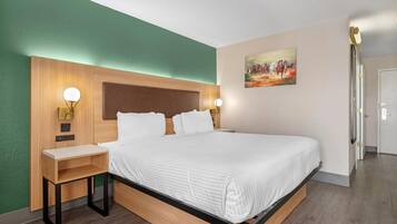 A neatly arranged hotel room with a bed, bedside tables, and a painting on the wall.