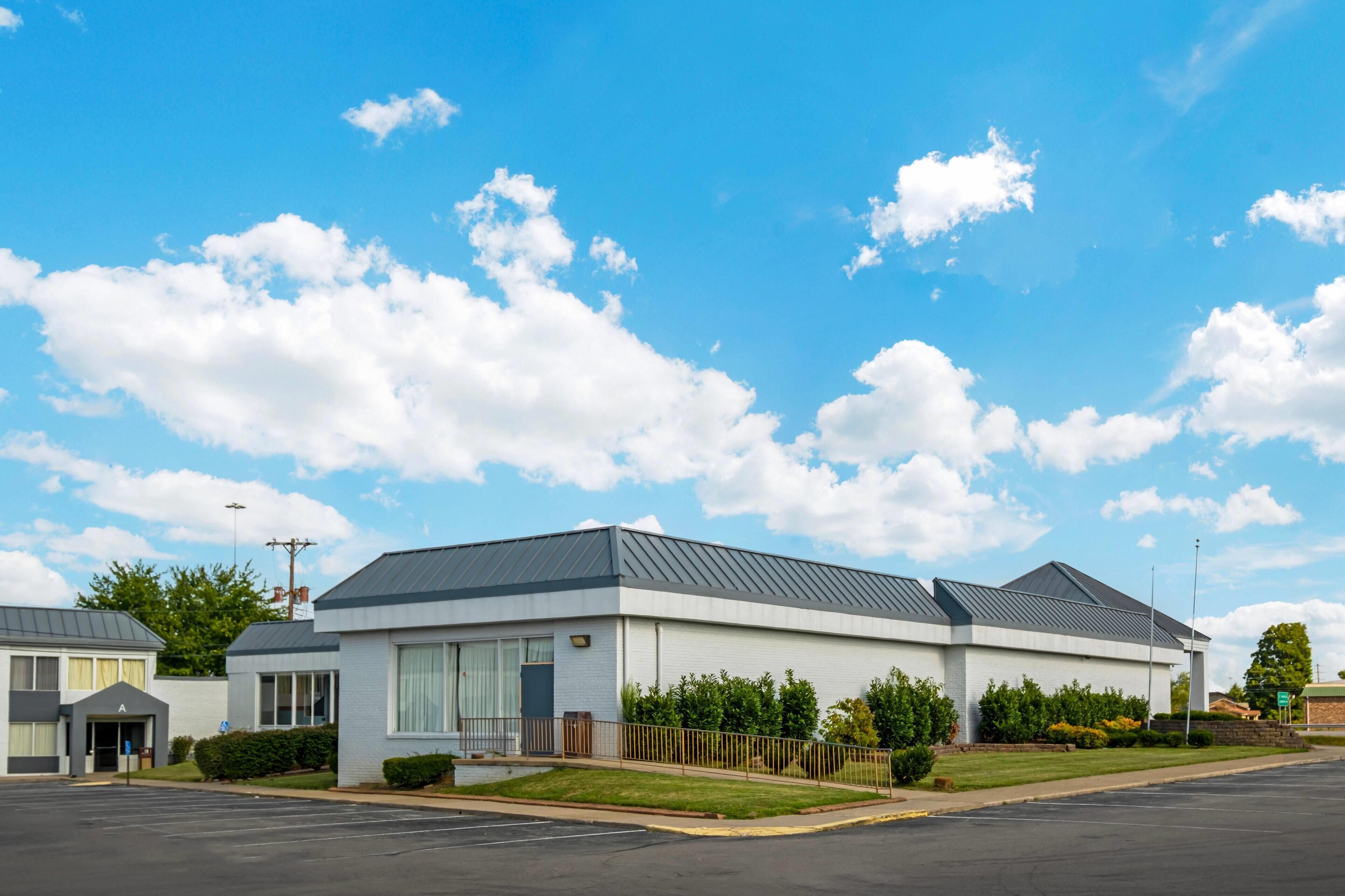 A modern building with a flat roof, large windows, and a parking lot.