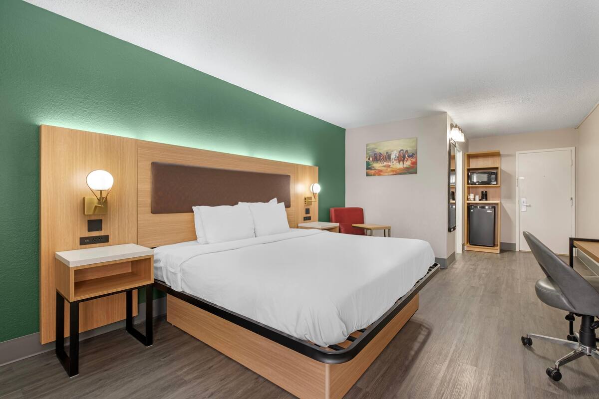 Une chambre d’hôtel équipée d’un lit, de tables de chevet, d’un bureau, d’une chaise, d’une armoire et d’un four à micro-ondes.