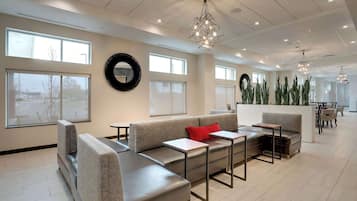 A modern lounge area with seating, tables, and large windows.