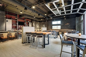 En modern restaurang med synliga tegelväggar, industriella rör i taket och en blandning av bar- och matområden.