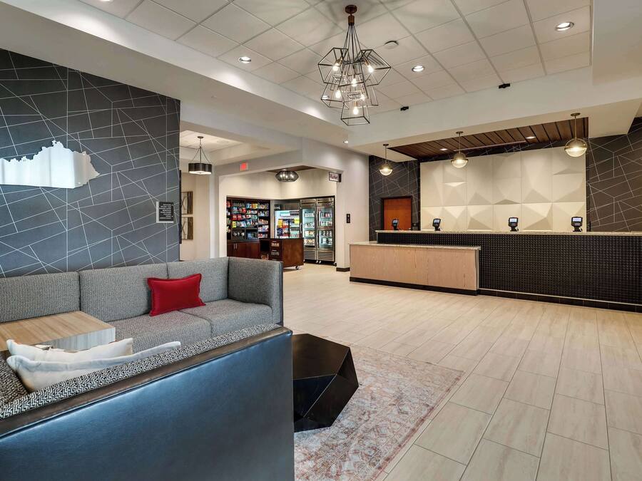 A modern lobby with a reception desk, a seating area with a sofa and a coffee table, and a patterned wall.