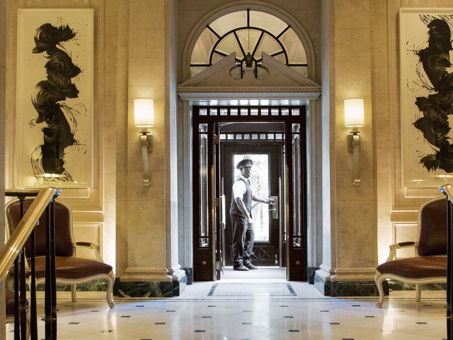 Un vaste hall d’entrée avec un sol en marbre, un plafond voûté et une porte d’entrée centrale.