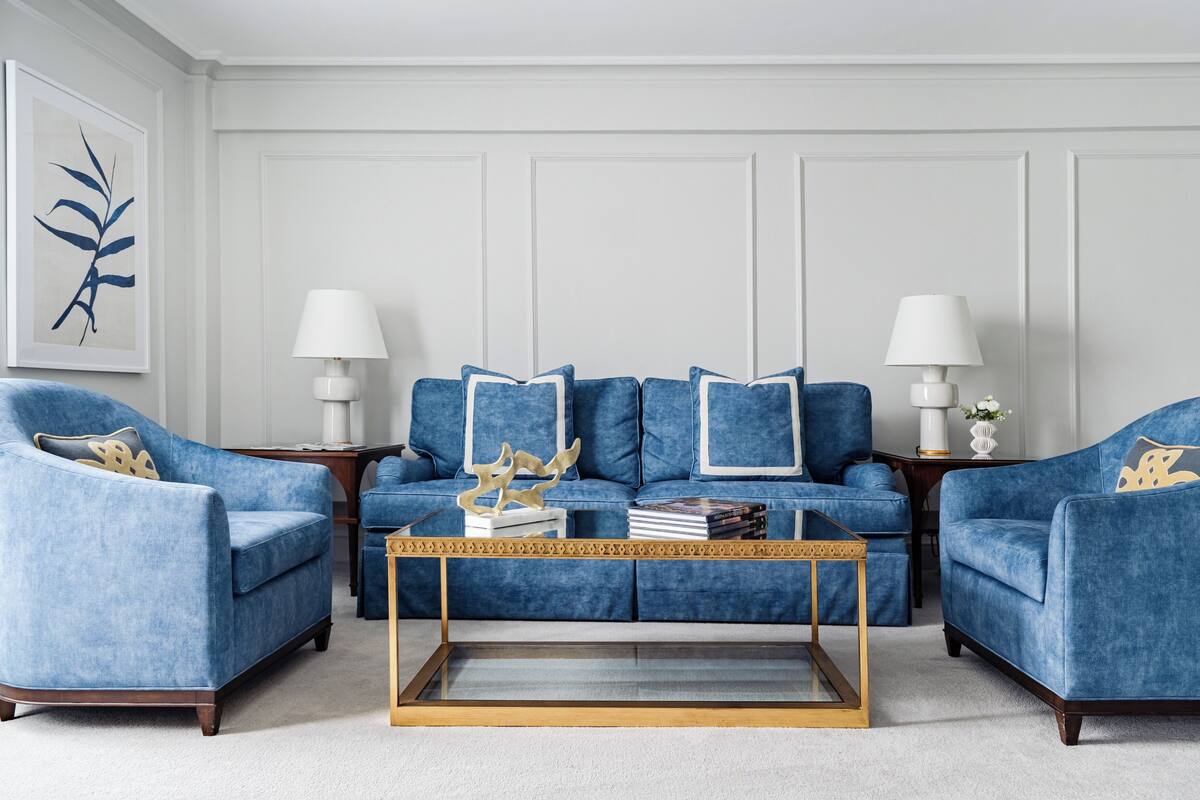 A living room with a blue sofa set, two side tables with lamps, and a coffee table with decorative items.