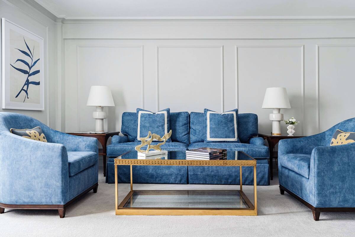 A living room with a blue sofa set, two side chairs, a coffee table, and decorative lamps.