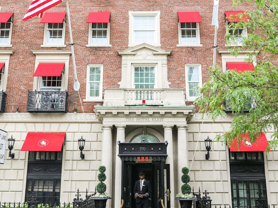 Un bâtiment en briques avec des auvents rouges, un drapeau et une enseigne indiquant « The Hotel Elliot ».