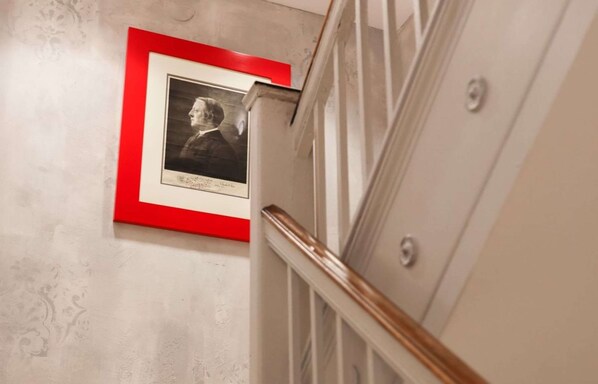 A staircase with a red-framed portrait on the wall.