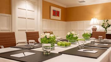 Une salle de conférence avec une longue table, des chaises et des compositions florales en guise de décoration.