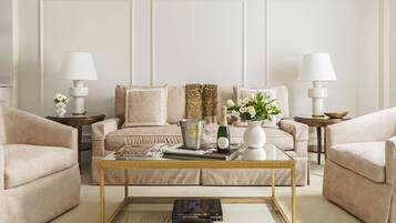 A living room with a beige sofa, two armchairs, a coffee table, and two side tables with lamps.