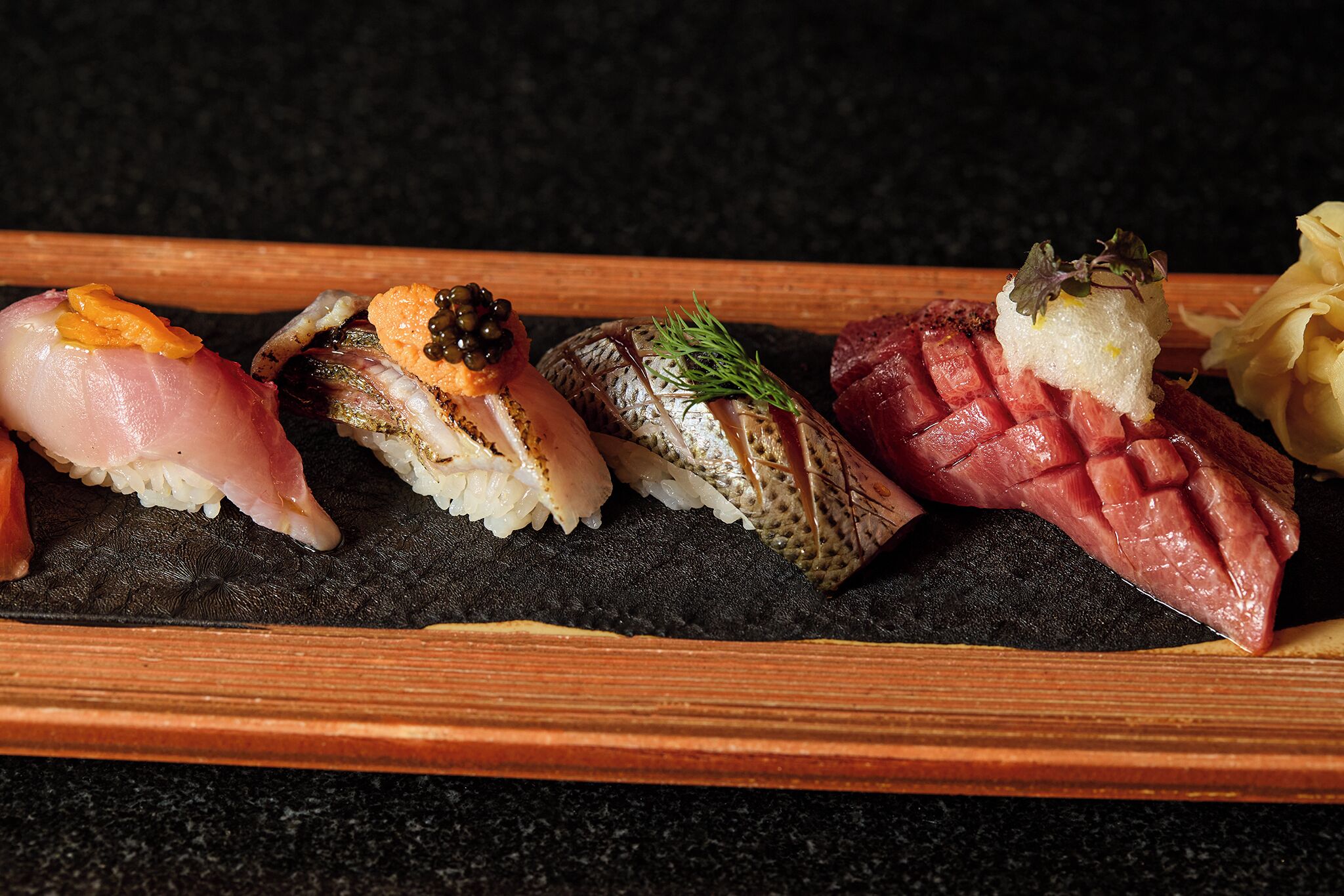 A wooden tray with various sushi pieces.