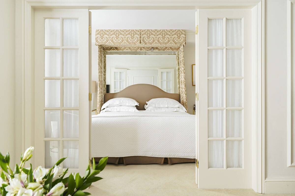 A bedroom with a large bed, white bedding, and a patterned headboard.