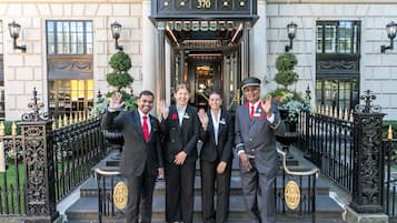 A group of four individuals standing in front of a building with a black entrance and the number 370.