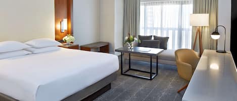 A hotel room with a large bed, a desk, a chair, and a TV.