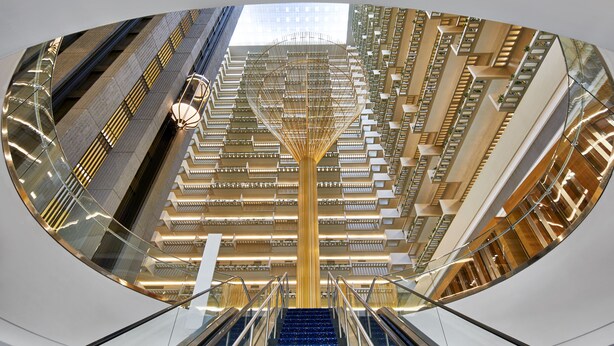 Un intérieur moderne doté d’un atrium central, de plusieurs niveaux et d’un plafond de verre qui reflète l’environnement extérieur.