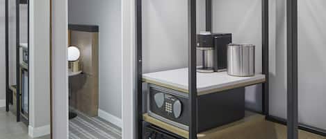 A bunk bed with a desk and a coffee machine, a mirror, and a small shelf with a lamp.