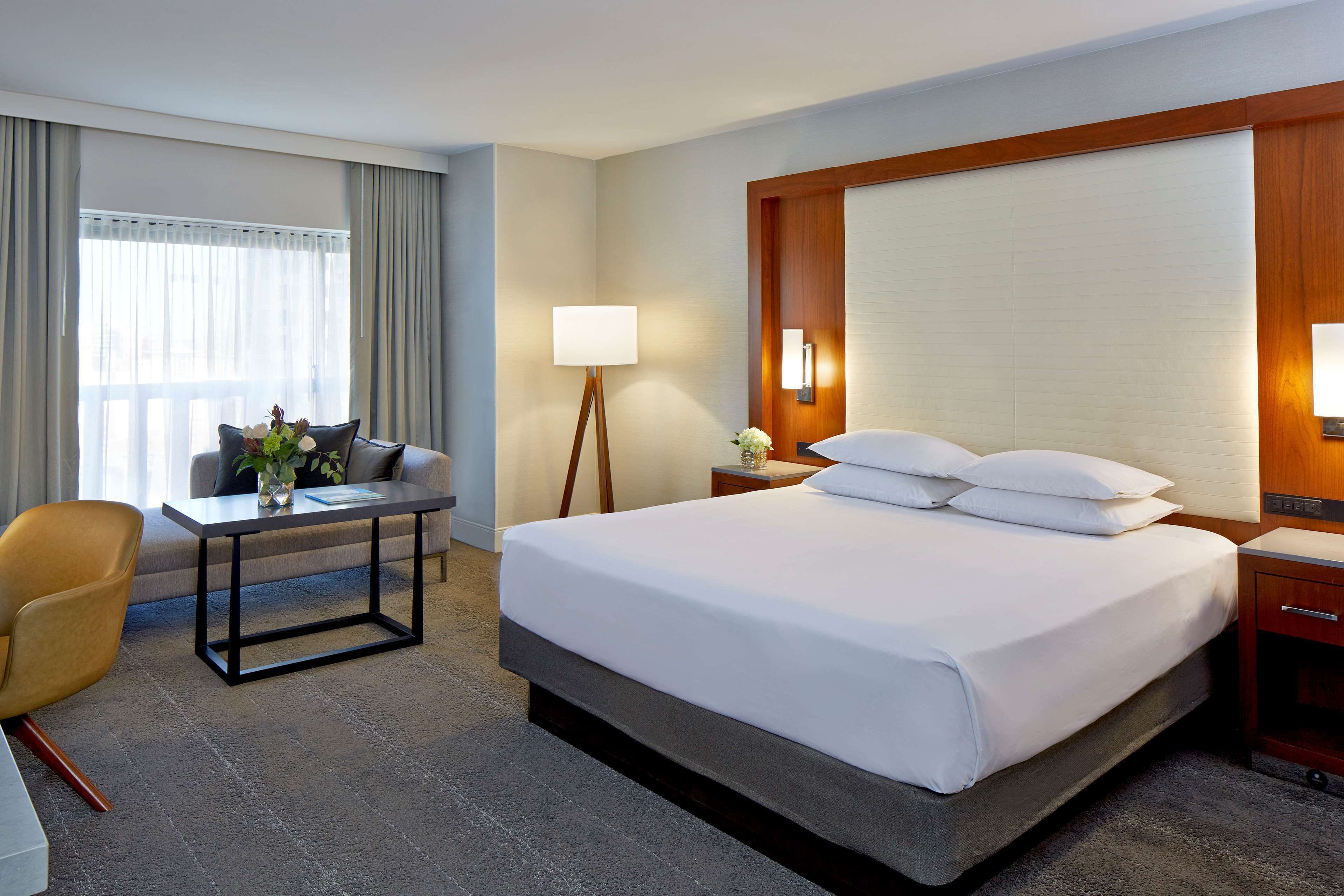 Ein Hotelzimmer mit einem großen Bett, einem Schreibtisch, einem Stuhl, einer Lampe und einem Nachttisch.