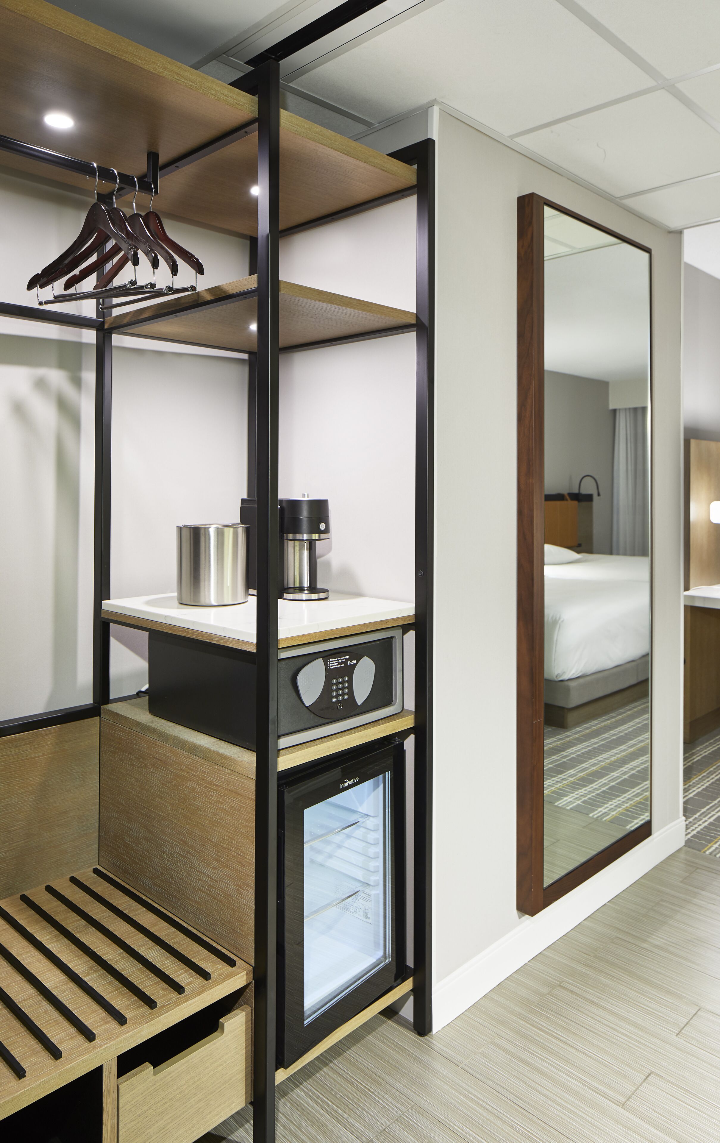 A hotel room with a built-in wardrobe, a coffee machine, and a mini-fridge.