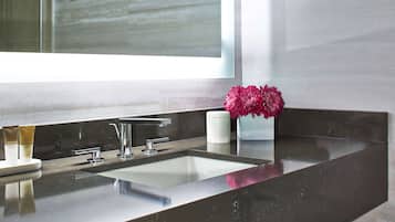 Une salle de bain moderne avec un grand miroir, un lavabo et un vase de fleurs.