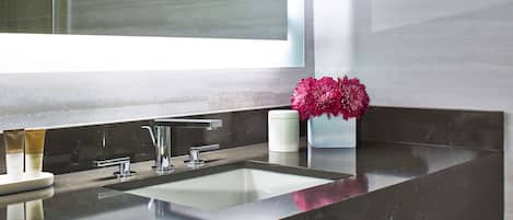 A modern bathroom with a large mirror, a sink, and a vase of flowers.