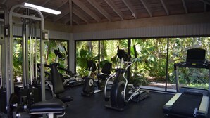A gym with various exercise equipment, large windows, and a view of greenery outside. - 1800 Atlantic Suites (Key West)
