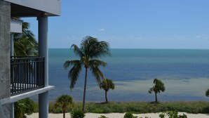A balcony with a view of the ocean and palm trees. - 1800 Atlantic Suites (Key West)